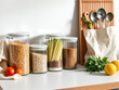 © Vectplus - Organized kitchen countertop with jars of grains, vegetables, and fresh herbs displayed in bright natural light