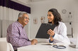 © fizkes - Latina woman doctor general practitioner holds clipboard, showing medical checkup results, explain medication prescription or diagnosis details to smiling aged 70s patient during appointment in clinic