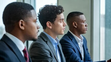 Poster - Three men in business attire engaged in a serious discussion by a window.