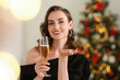 © New Africa - Smiling woman with glass of sparkling wine celebrating Christmas at home