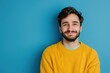 © darshika - Man in yellow sweater smiling in photo on blue background.