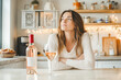 © ЮРИЙ ПОЗДНИКОВ - Woman drinking rose wine contemplating in kitchen during holidays