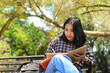 © M Alfan Setyawan - smiling asian beautiful young woman enjoy writing to do list and idea in notebook in outdoors city park