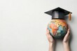 © nattapon - A pair of hands holds a globe adorned with a graduation cap, symbolizing education and global achievement, Ideal for educational content, graduation announcements, or international studies,