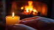 © Ashalina - Hands holding a lit candle near a fireplace.