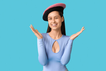 Wall Mural - Beautiful young woman in stylish beret hats on blue background