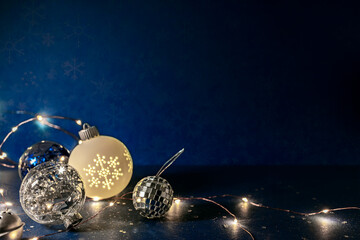 Wall Mural - glass balls with glowing holiday garland lights. christmas decorations on dark blue background.