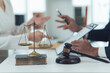 © Kritdanai - Justice Scales and Gavel:  A close-up shot of a judge's gavel, scales of justice, and legal documents on a table, suggesting a courtroom setting or legal consultation. Implies fairness, judgment.