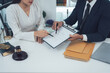 © Kritdanai - Legal Consultation:  A lawyer and client review documents together, signifying trust and legal process.  The image shows a serious and professional atmosphere.