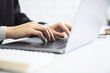 © Who is Danny - Woman's hands, in close-up, typing on a stylish laptop keyboard, amidst a blurry office setting