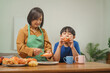 © NanSan - A mother and her children prepare fresh bread, milk, and fruits for breakfast, enjoying a productive and joyful morning together, creating a healthy and nourishing start to their day