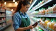 © useful pictures - A grocery store employee in a green apron examines inventory on a tablet while comparing it to the stock on shelves filled with various products
