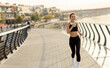 © BGStock72 - Joyful jogger enjoying a morning run along a scenic riverside promenade on a clear day, with beautiful views and gentle breeze