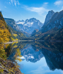 Wall Mural - Peaceful autumn Alps mountain lake with clear transparent water and reflections. Gosauseen or Vorderer Gosausee lake, Upper Austria. Dachstein summit and glacier in far.