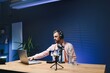 © Serhii - vlogger using smartphone to film podcast in studio. blogger with mobile phone, microphone and headphones filming video for social media broadcasting career