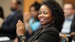 © 69 - A professional black woman clapping in appreciation during a lively seminar, seated among an engaged audience in a modern conference setting