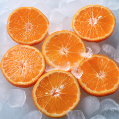 Background of beautiful mandarine orange fruit slices on frozen surface