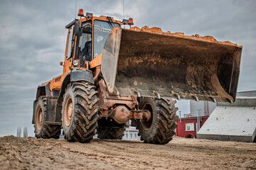 heavy loader excavates soil on a construction site under overcast skies, showcasing the powerful mac