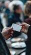 © MIN_NK - A hand exchanges a blank card among a crowd, symbolizing networking, communication, and opportunities in a social setting.