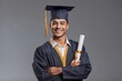© RulArt - Studio portrait of satisfied student with his graduation certificate. Happy academy, college or university graduate standing against gray background, holding his diploma scroll and smiling at camera