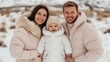 © mangolovemom - A happy family in winter clothing poses together in the snow, showcasing warmth and togetherness in a beautiful outdoor setting.