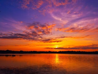 Wall Mural - vivid colorful color of sunset with clouds.sunset with mountain above lake reflection in water.