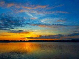 Wall Mural - vivid colorful color of sunset with clouds.sunset with mountain above lake reflection in water.