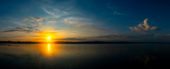 Wall Mural - vivid colorful color of sunset with clouds.sunset with mountain above lake reflection in water.