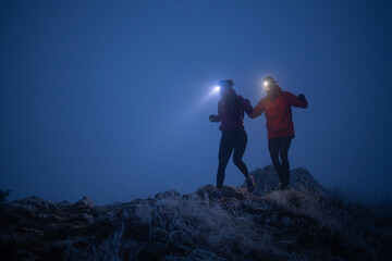 Night trail runner of men and women running on the mountain.at night milky way