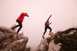 © .shock - trail runner couple jumping over a cliff and running to a rocky mountain top in the early morning or night