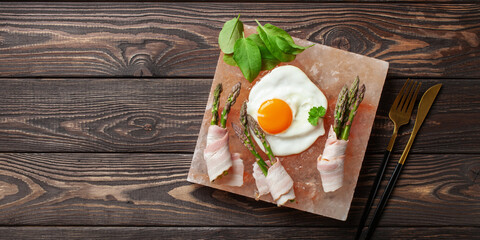 Wall Mural - Scrambled eggs and asparagus with bacon on a salt block. Himalayan pink salt block kitchen concept. Top view