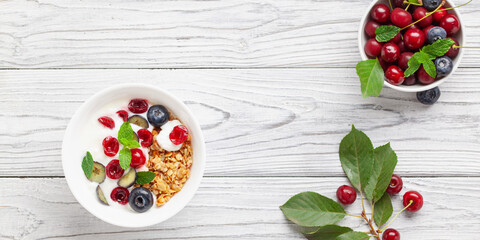 Wall Mural - Cherry and blueberry granola with yogurt. Healthy food, diet breakfast. Top view