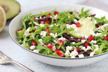 Wall Mural - A plate with green rocket salad with pomegranate and avocado