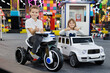 © Studio Peace - Happy children, a boy and a girl, are riding cars and motorcycles in a modern playroom.