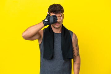 Wall Mural - Young sport caucasian man with towel isolated on yellow background covering eyes by hands. Do not want to see something