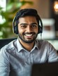 © Johannes - Happy indian business man remote teacher, customer support manager wearing headset talking at virtual meeting consulting client on video call giving distance learning class at home office call center