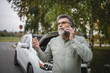 © Miljan Živković - worried man stand in front open hood of car make a phone call for help