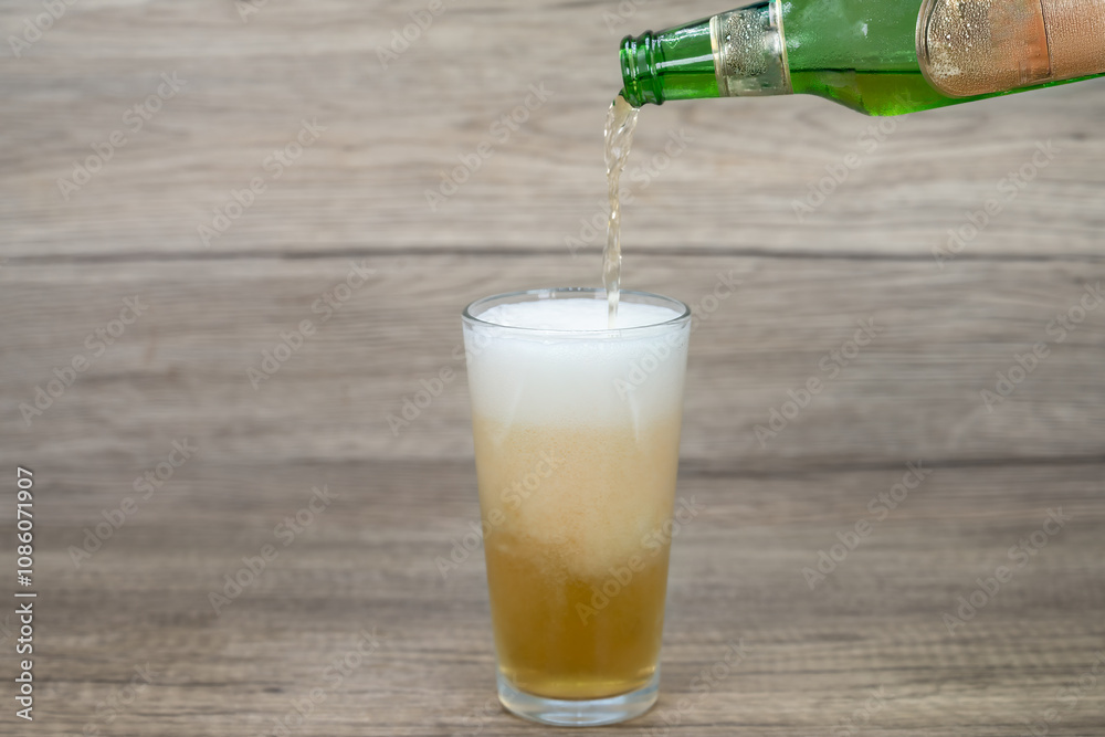 Ice cold draft beer poured into a pint glass with foaming suds filled ...