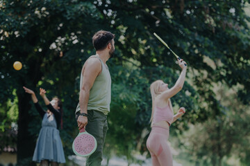 Poster - A group of friends plays badminton in a sunlit park, showcasing friendship, outdoor activity, and leisure. The image captures joyful interaction and active lifestyle in a natural setting.