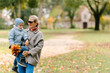 © Elena - Autumn mood, a boy walking with his father and mother in an autumn village against the background of an old house and autumn trees, the boy holds a bouquet of maple leaves in his hands