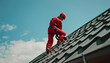 © Oleksiy - Young man worker master in red overall and helmet is fixing the metal tile roof