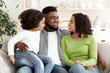 © Prostock-studio - Portrait of happy black family resting together on couch at home, cuddling and smiling, enjoying time together, free space