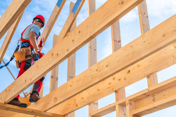 Construction Worker Installing Roof Trusses on a Sunny Day at a Building Site