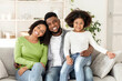 © Prostock-studio - Family Insurance Concept. Portrait Of Happy Black Father, Mother And Little Daughter Posing On Couch At Home