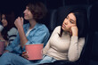 © Prostock-studio - Dull date concept. Bored young lady with boyfriend watching movie in cinema