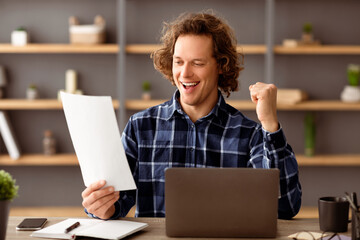 Poster - Yes, I Did It. Joyful Entrepreneur Guy Celebrating Business Success Shaking Fists Holding Papers Sitting At Workplace In Modern Office. Great News, Successful Career Concept. Selective Focus