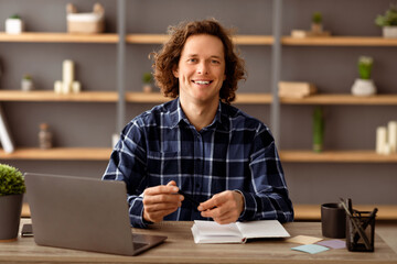 Poster - Happy Young Businessman Posing Sitting At Laptop And Smiling To Camera At Workplace In Office. Millennial Entrepreneur's Portrait. Business People, Modern Entrepreneurship Concept