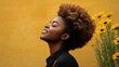© julio - Woman with curly hair smiling beside yellow flowers against a backdrop.
