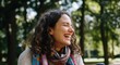© Tati - Smiling woman with curly brown hair in outdoor park setting