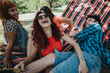 © qunica.com - A group of friends laughing and enjoying a sunny day outdoors in a colorful hammock. They are having fun and sharing happy moments together.